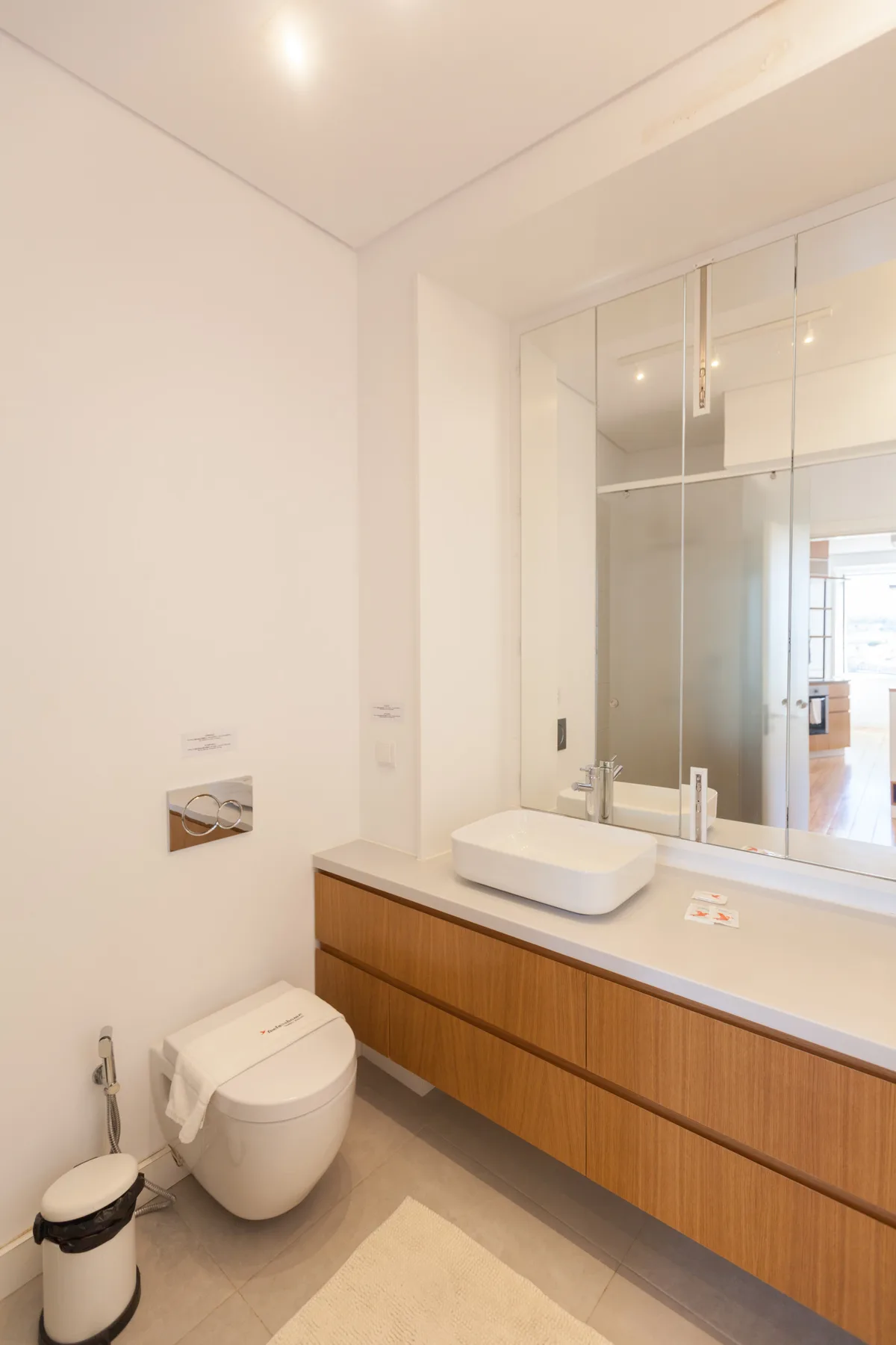 Un baño luminoso con inodoro, lavabo y un espejo grande.