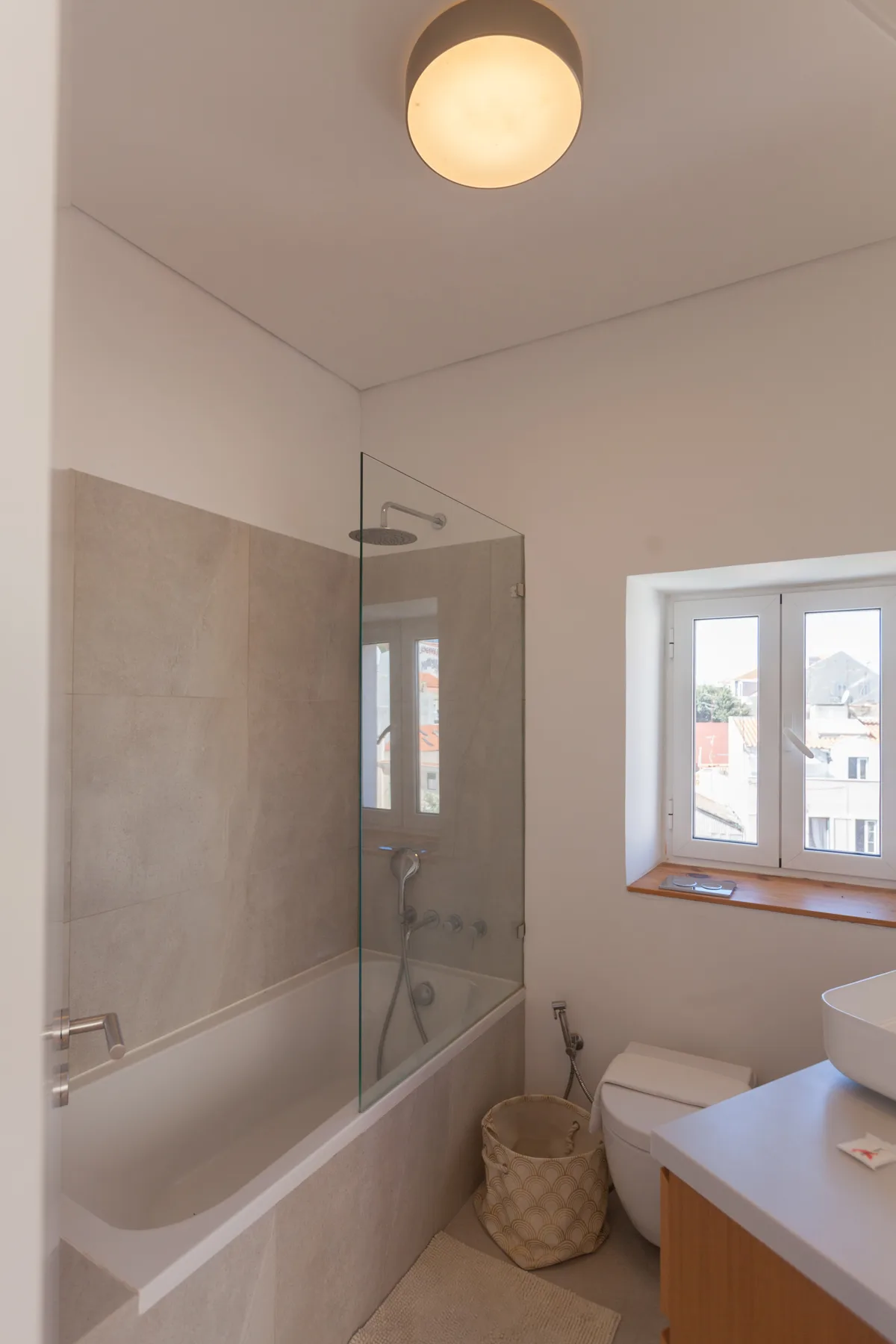 Baño con bañera, mampara de vidrio y ventana.