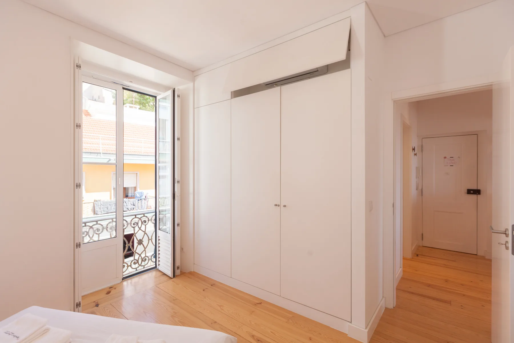 Un dormitorio luminoso con un armario empotrado y una puerta abierta al balcón.