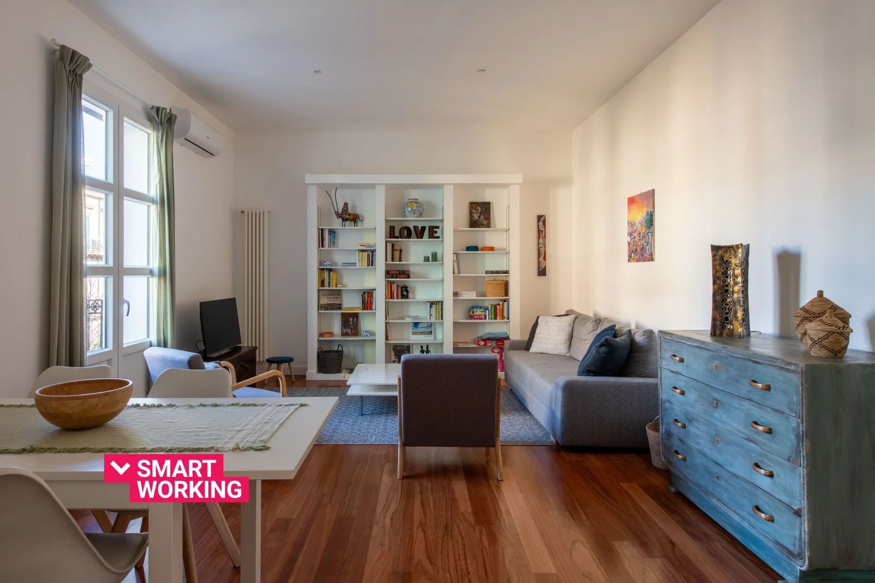 A bright living room with a gray seating area and a wall of bookshelves.