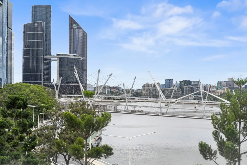 El perfil urbano se alza detrás de un río y un puente blanco.