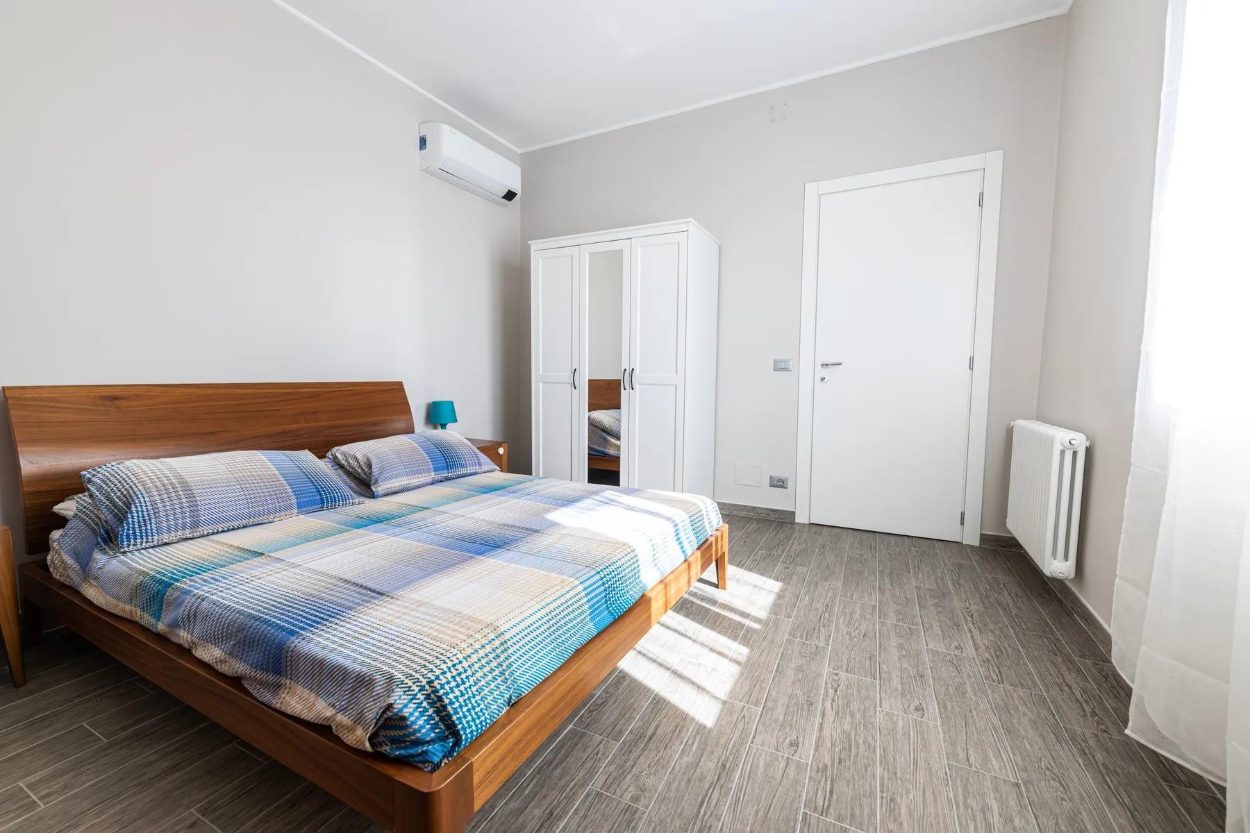 Un dormitorio con una cama doble, un armario y una puerta cerrada.