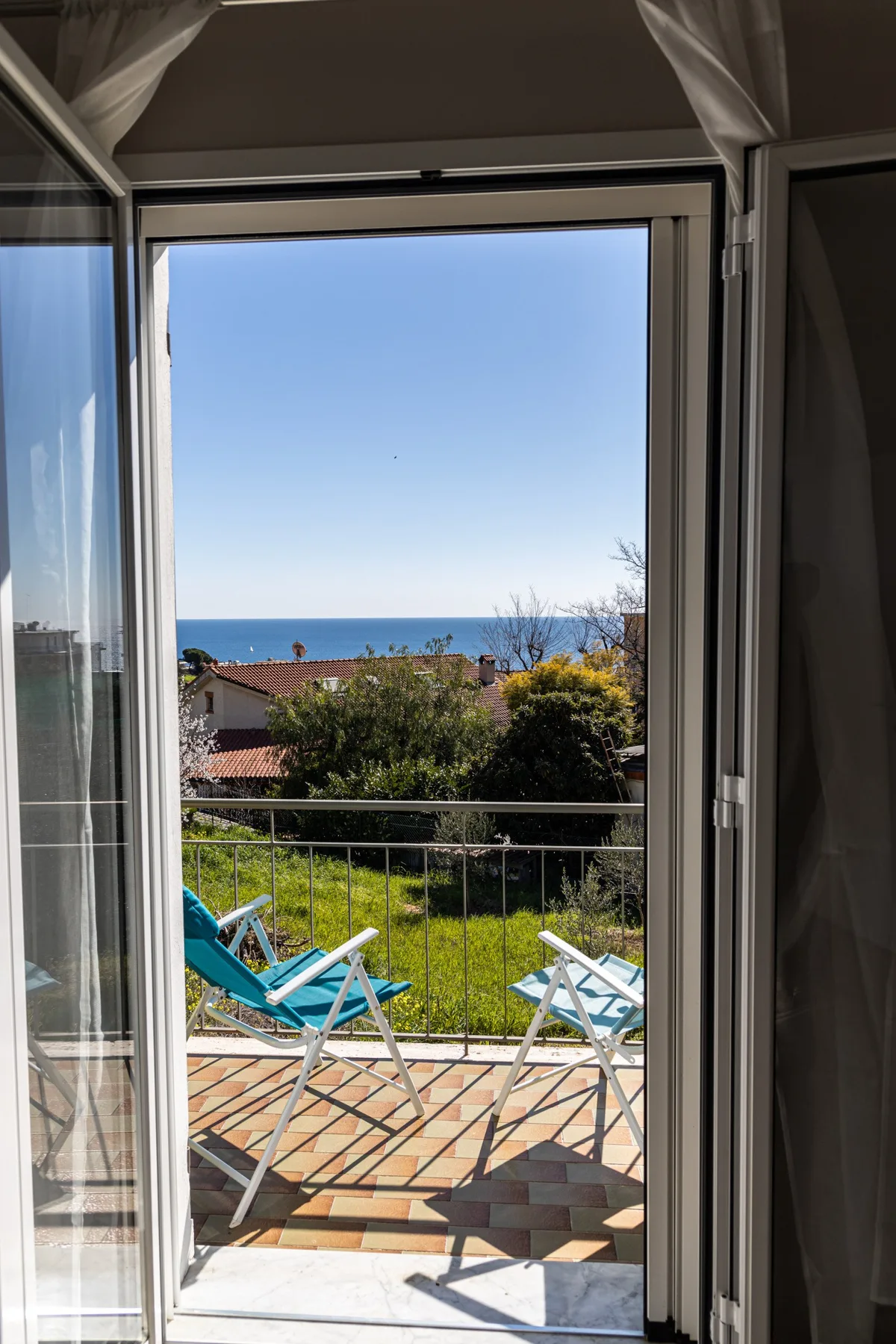 Una puerta abierta da a un patio, un jardín y el mar.