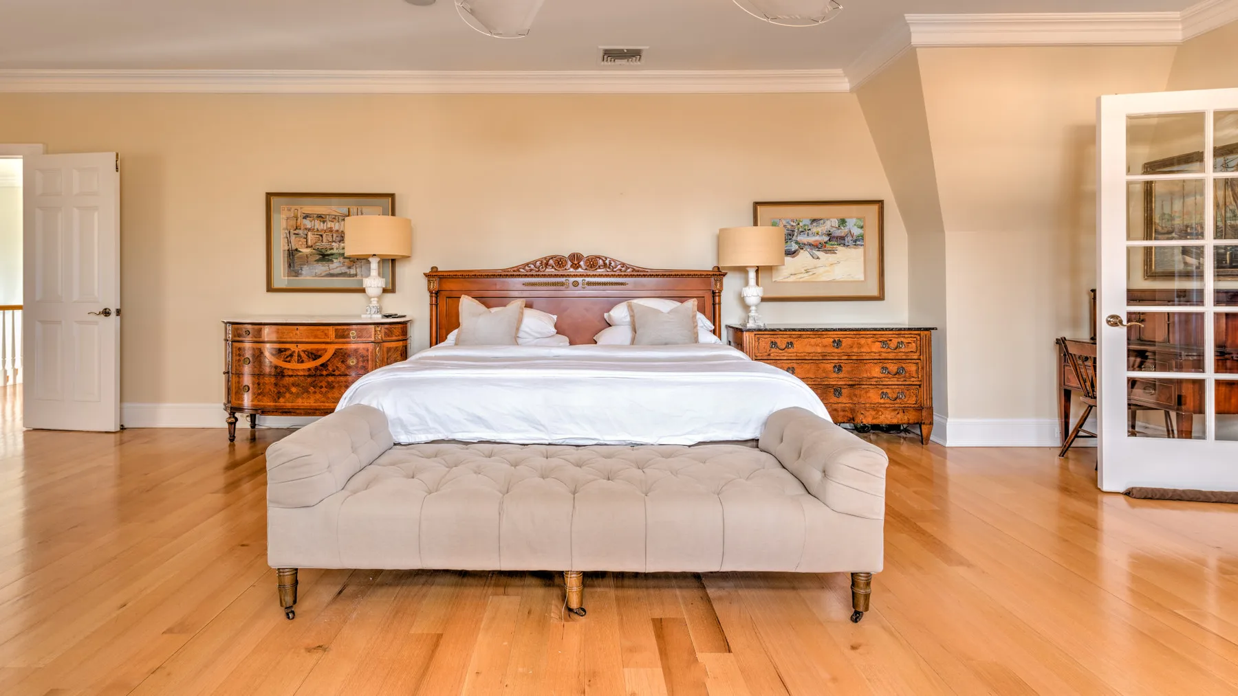 A bedroom with a large bed centered between two wooden dressers.