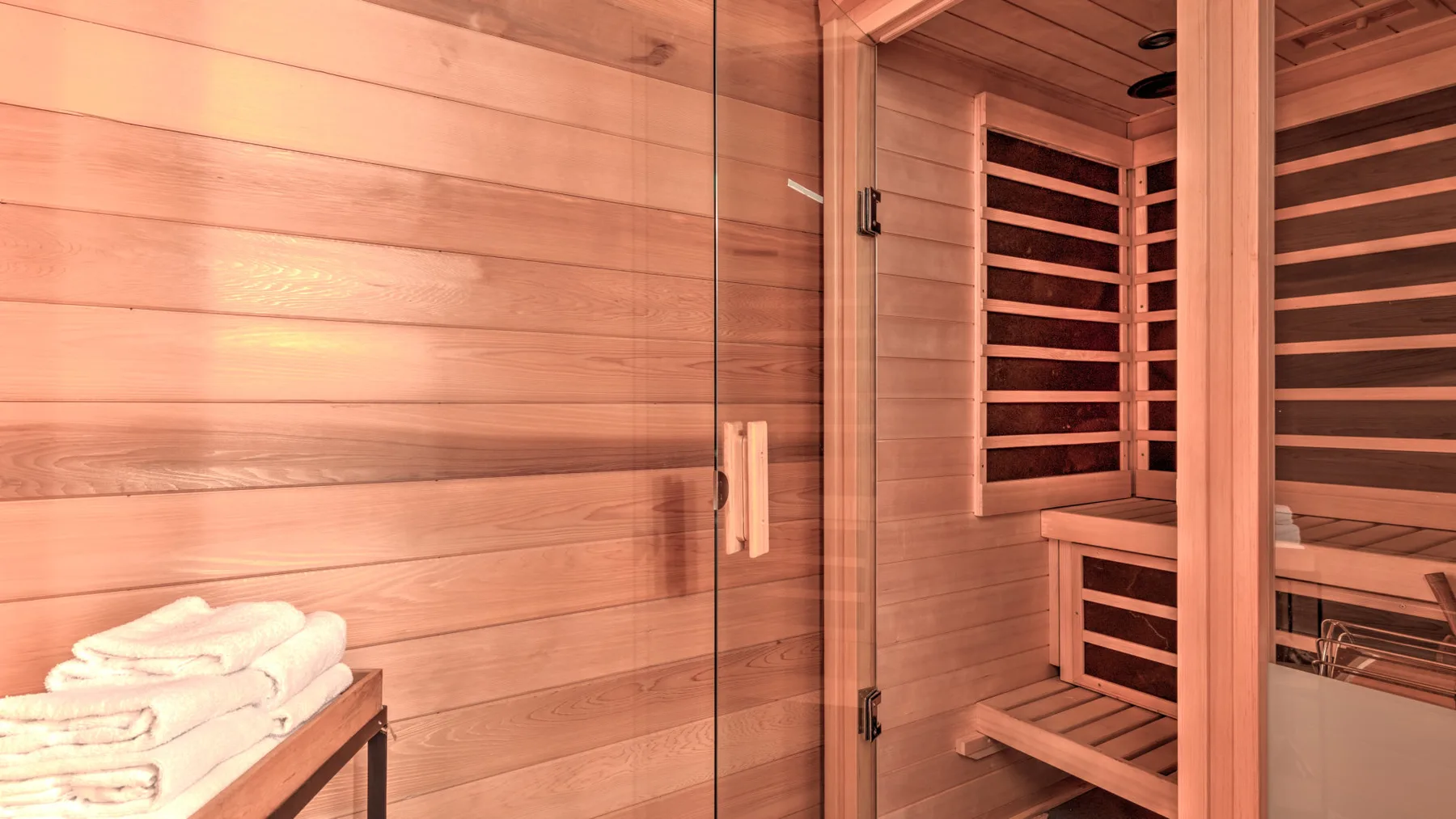 A wood-paneled sauna with tiered seating and folded towels.