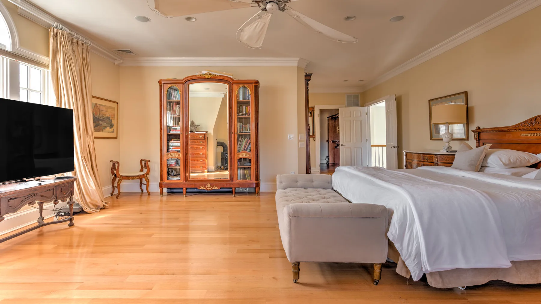 A bedroom with a bed, an upholstered bench, and a glass-front cabinet.