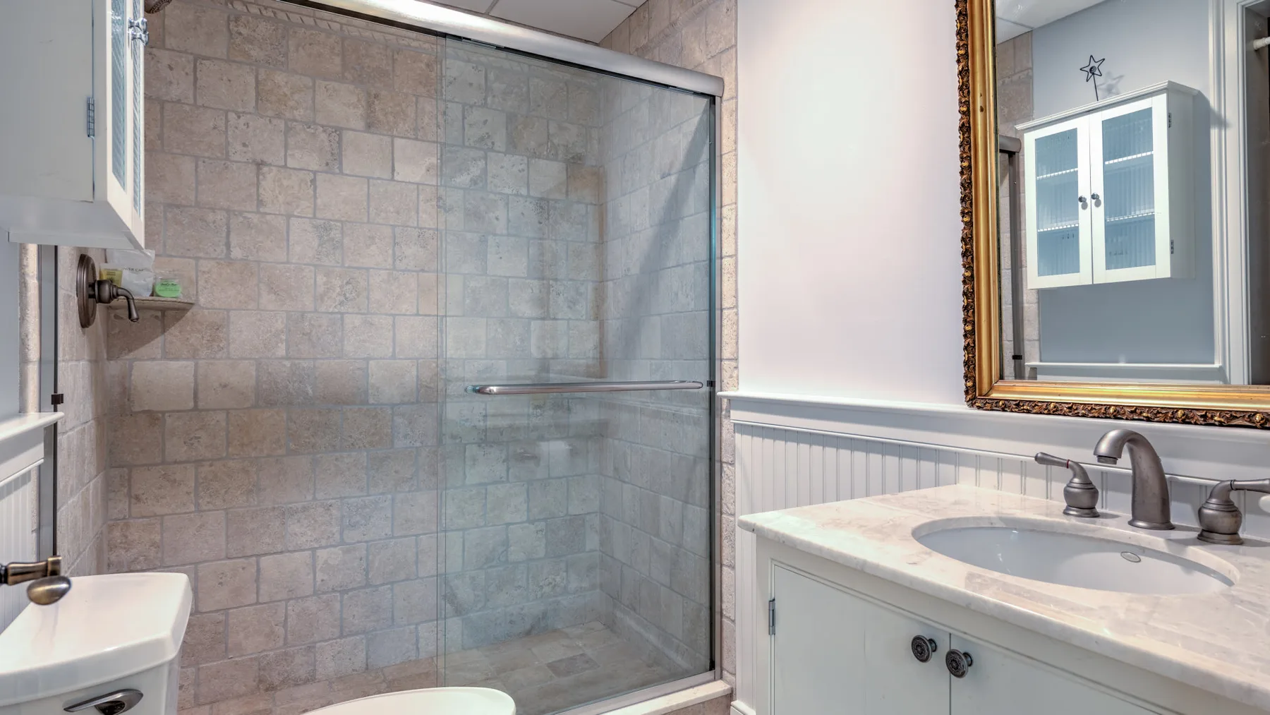 A bathroom with a glass shower and a sink vanity.