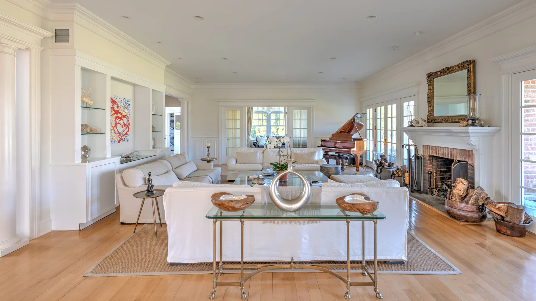 A bright living room with seating, a fireplace, and a grand piano.