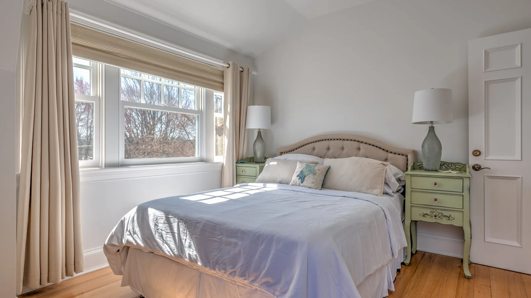 A bedroom with a neatly made bed beside a large window.