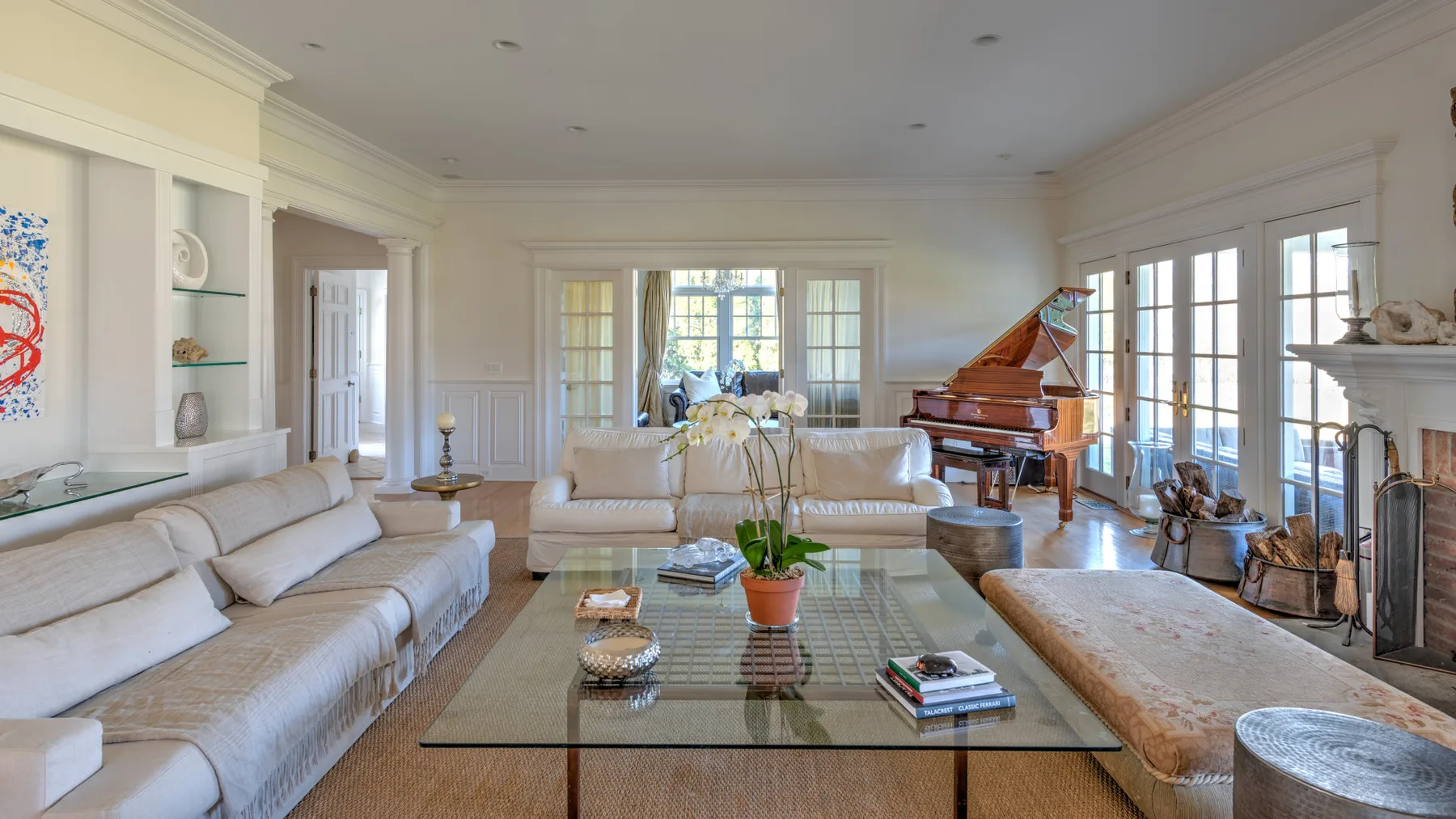 A bright living room with seating, a glass coffee table, and a grand piano.