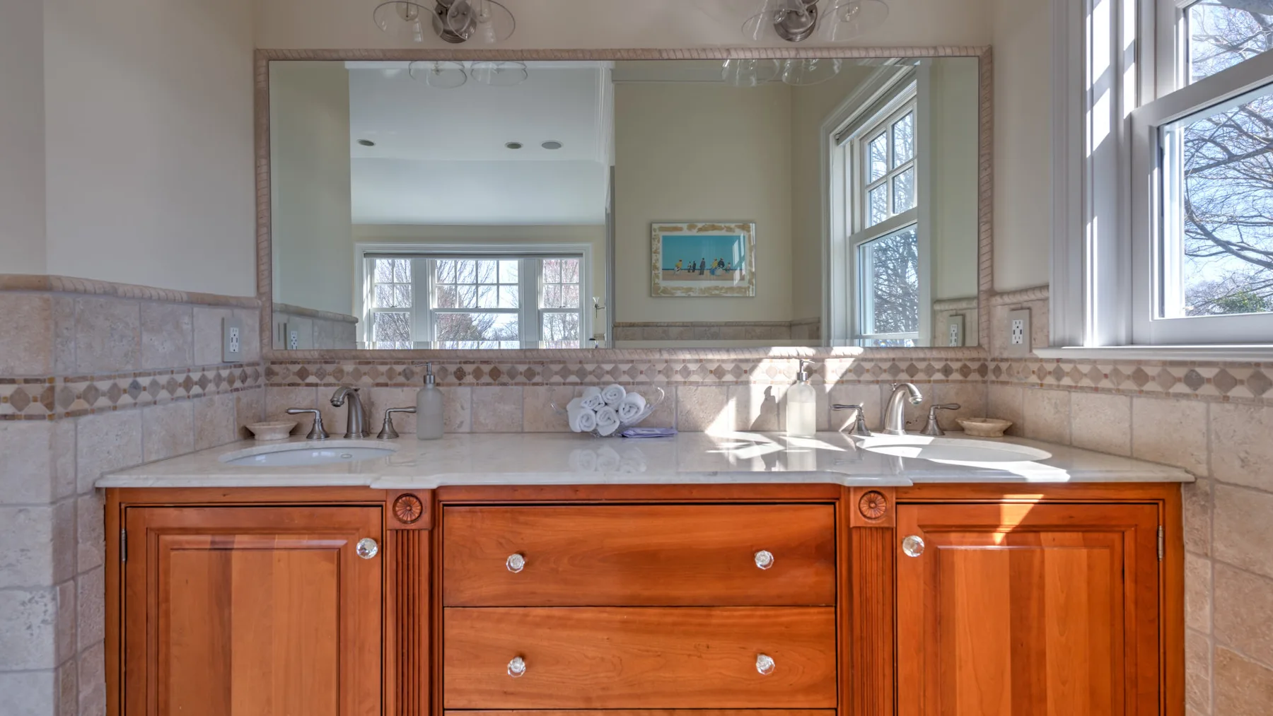A bathroom vanity with a broad mirror and a light-colored countertop.