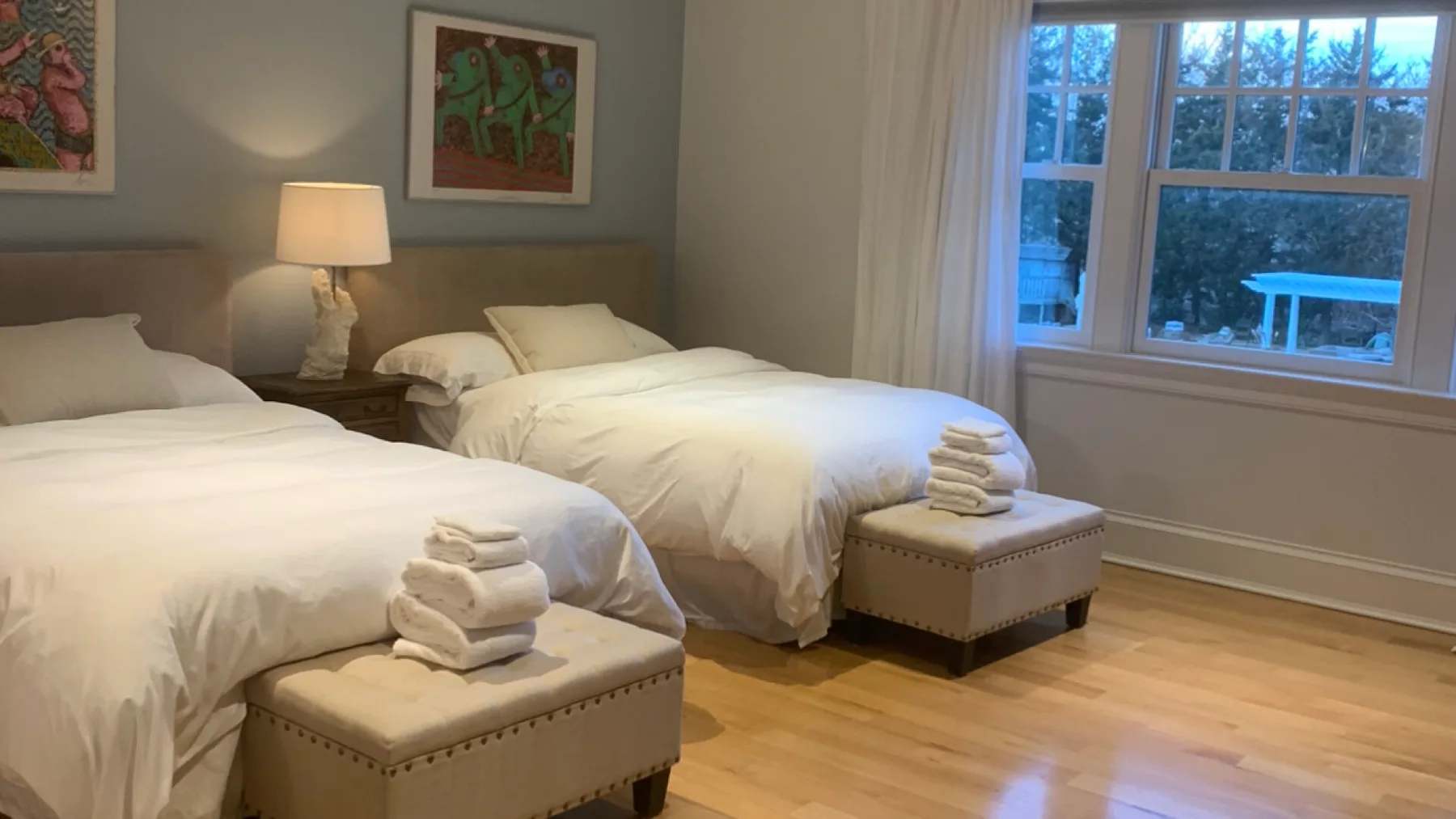 A bedroom with two beds, white bedding, and a large window.
