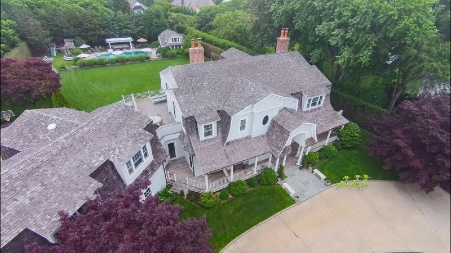 An aerial view of a large house with a curved driveway and green landscaping.