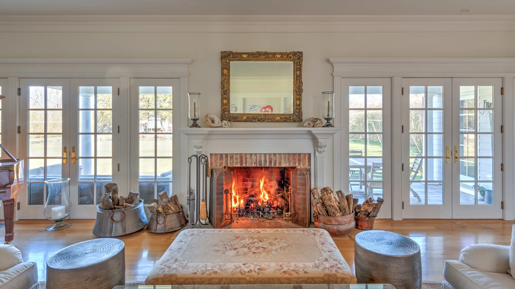 A bright living room centers on a fireplace between tall glass doors.