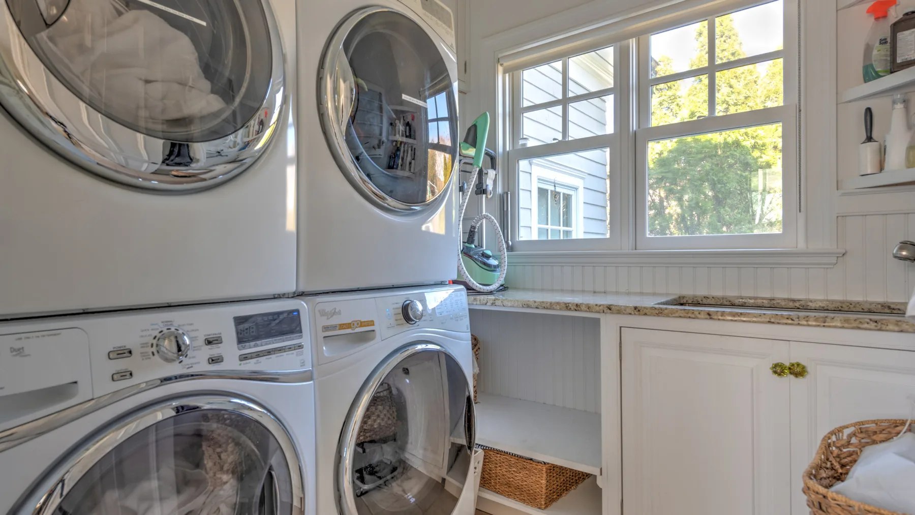 A laundry room with stacked front-loading appliances beside a window.