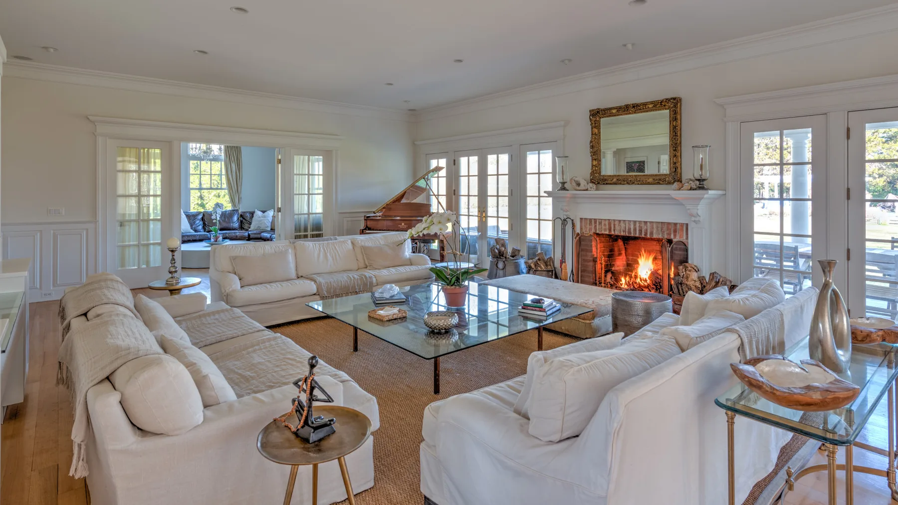 A bright living room with seating around a glass coffee table and a fireplace.