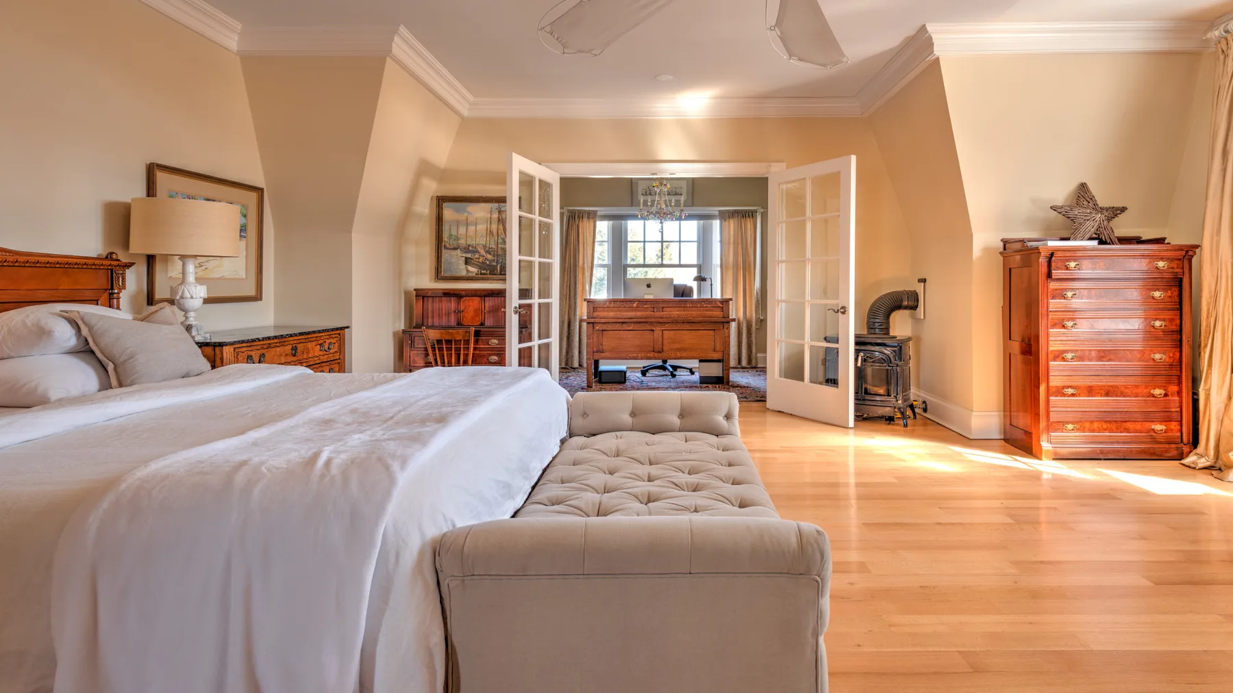 A bedroom with a large bed, a cushioned bench, and wooden furnishings.