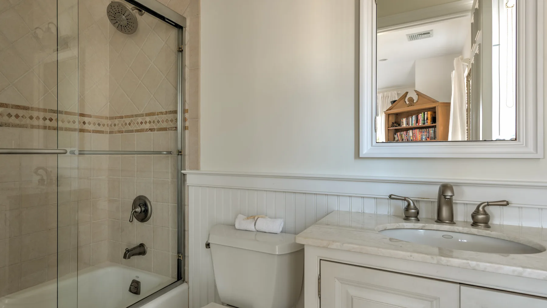 A bathroom with a glass shower, toilet, and sink.