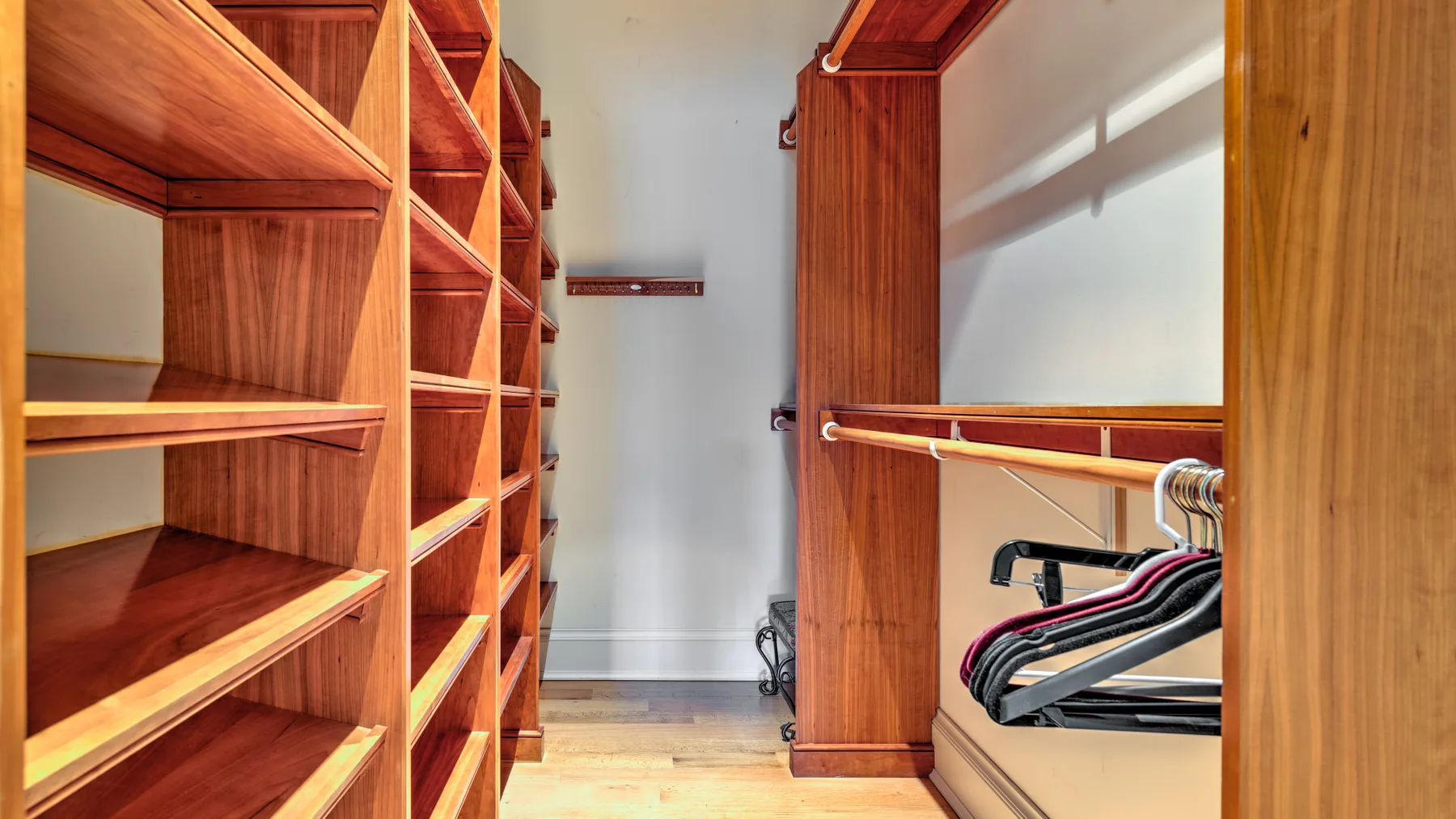 A walk-in closet with wooden shelving and hanging clothes.