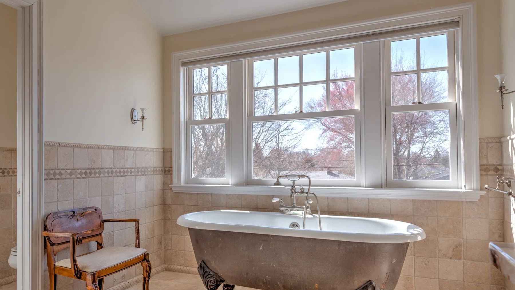 A bathroom with a freestanding bathtub beneath a large window.