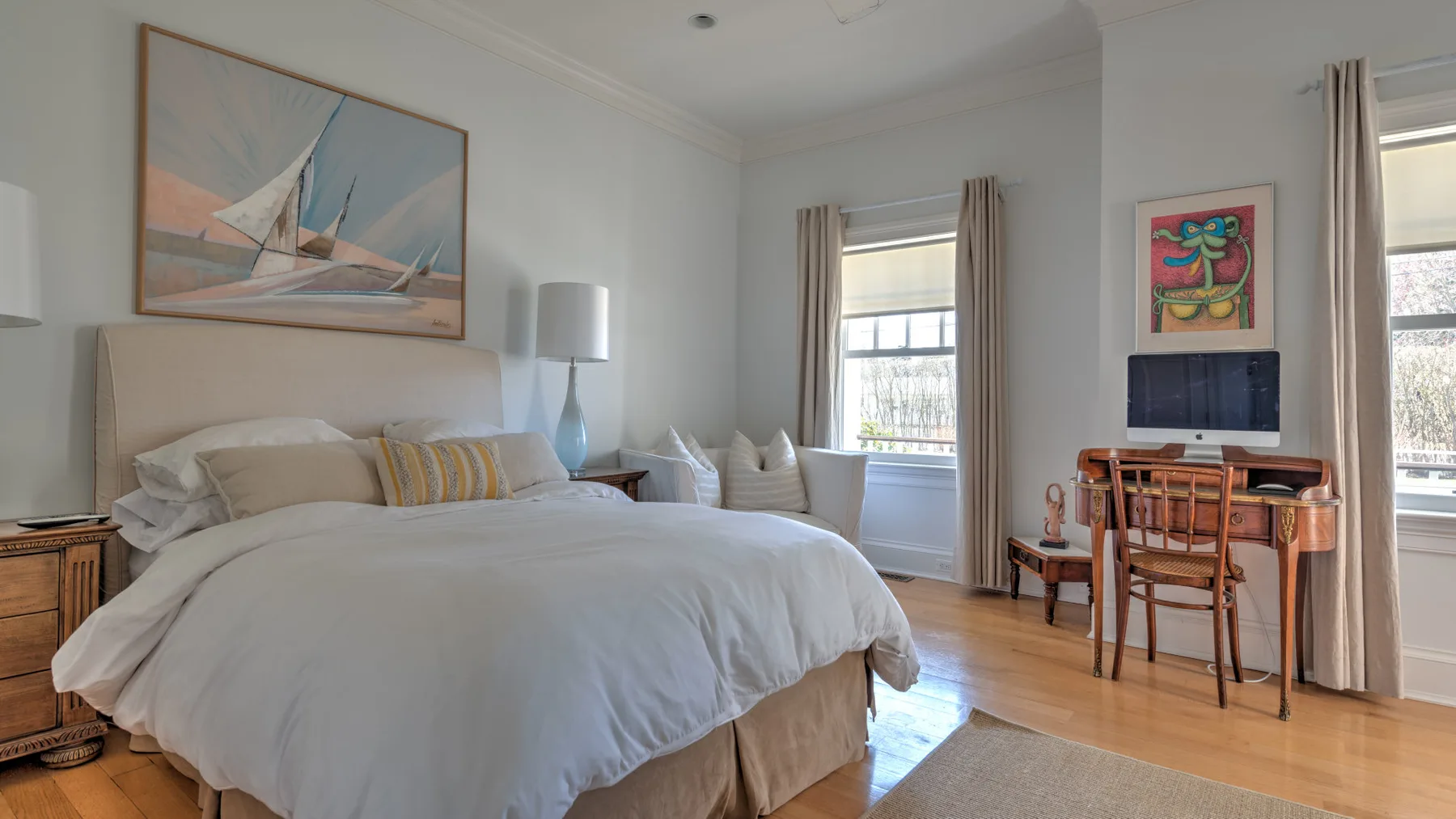 A bright bedroom with a neatly made bed and a desk by the window.