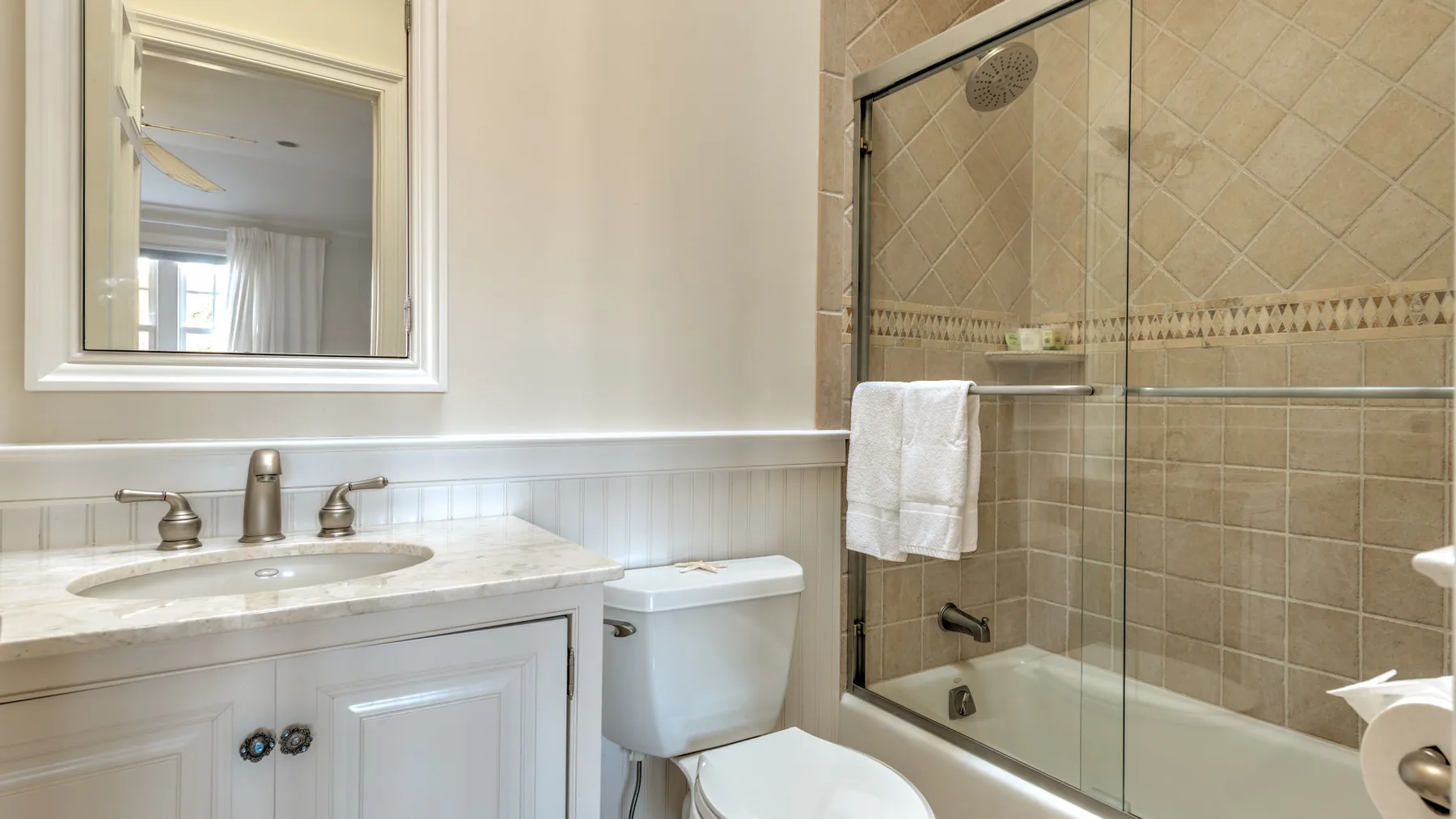 A bathroom with a sink vanity, toilet, and glass-enclosed shower.