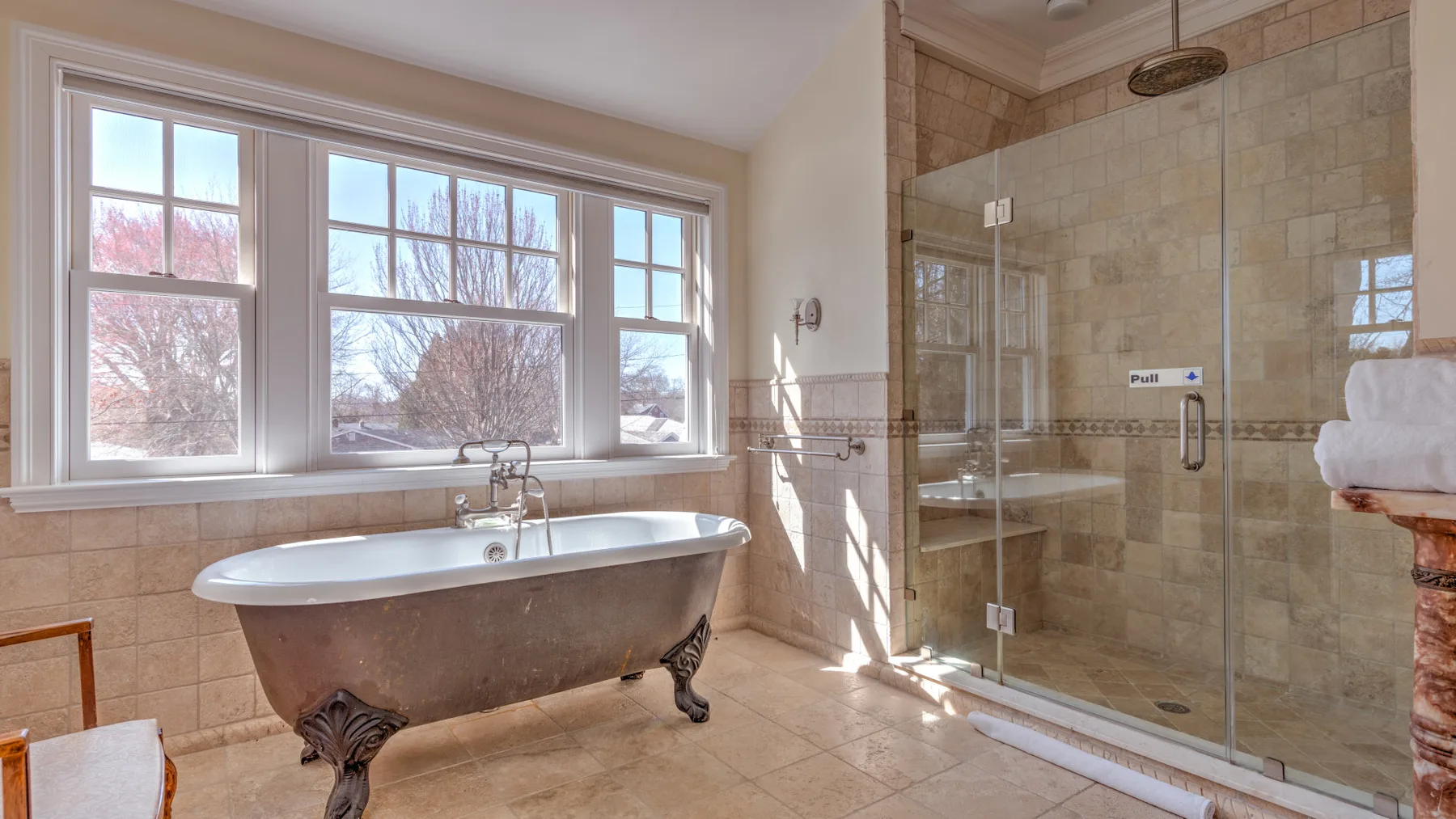 A bright bathroom with a freestanding bathtub beside a glass shower.