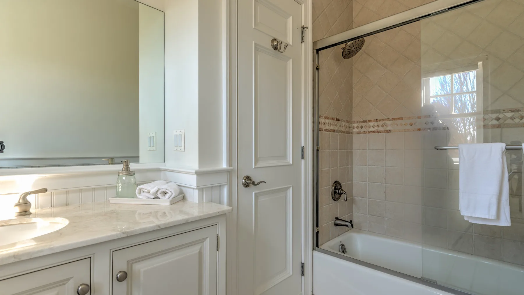 A bathroom with a vanity beside a tiled tub and shower.