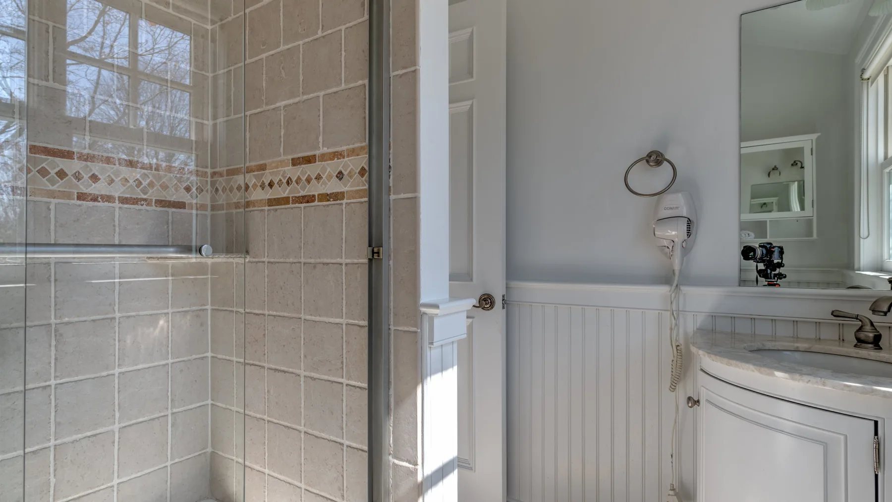 A bathroom with a tiled shower and a white vanity.