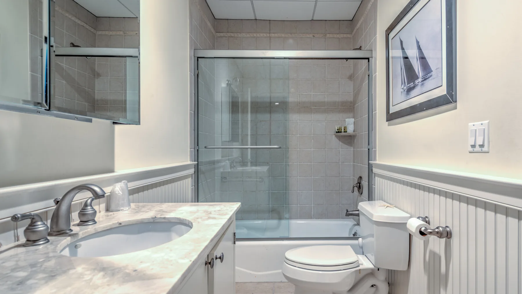 A bathroom with a glass shower enclosure, bathtub, toilet, and vanity.