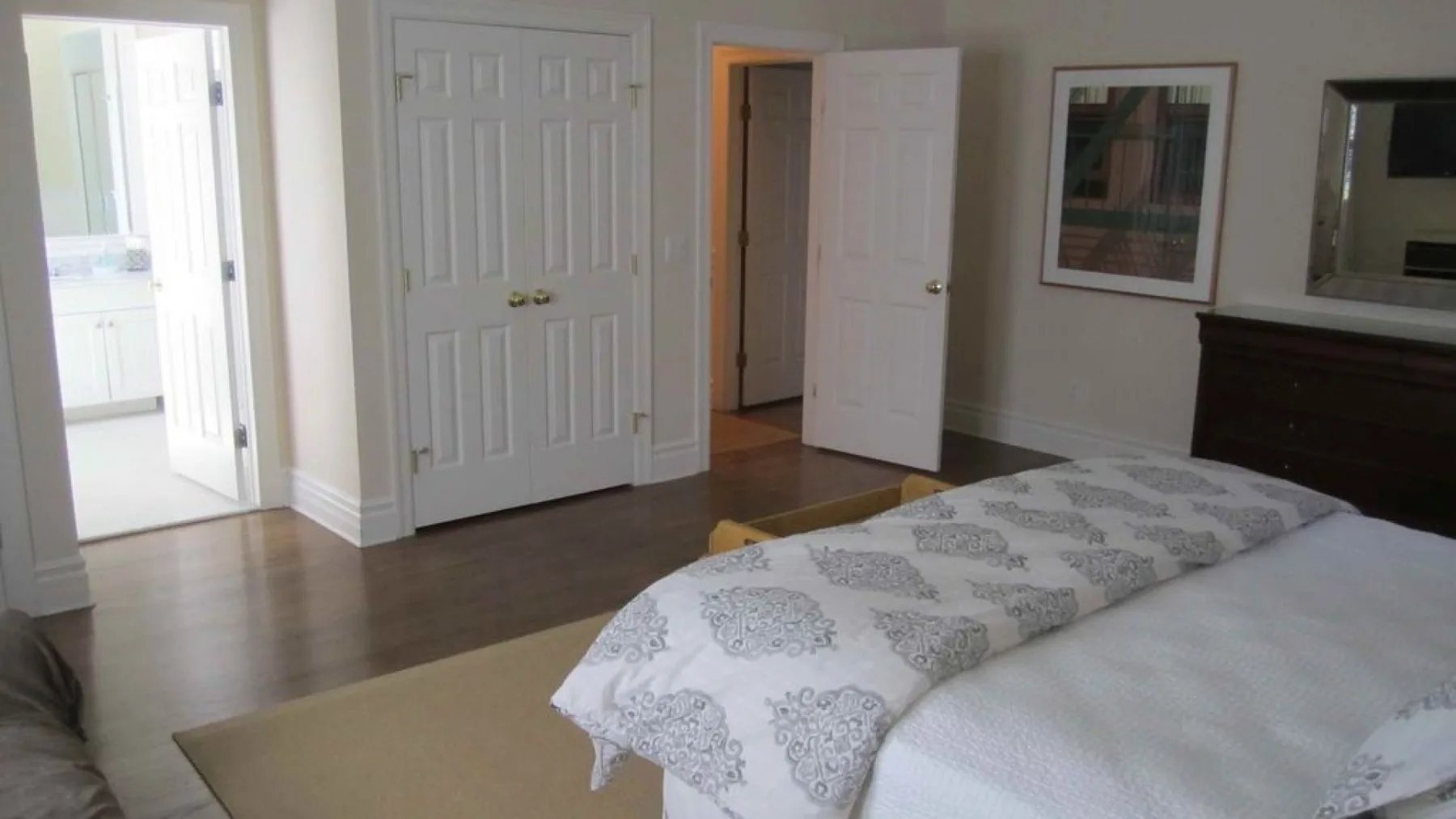 A bedroom with a bed covered in patterned bedding and open doors.