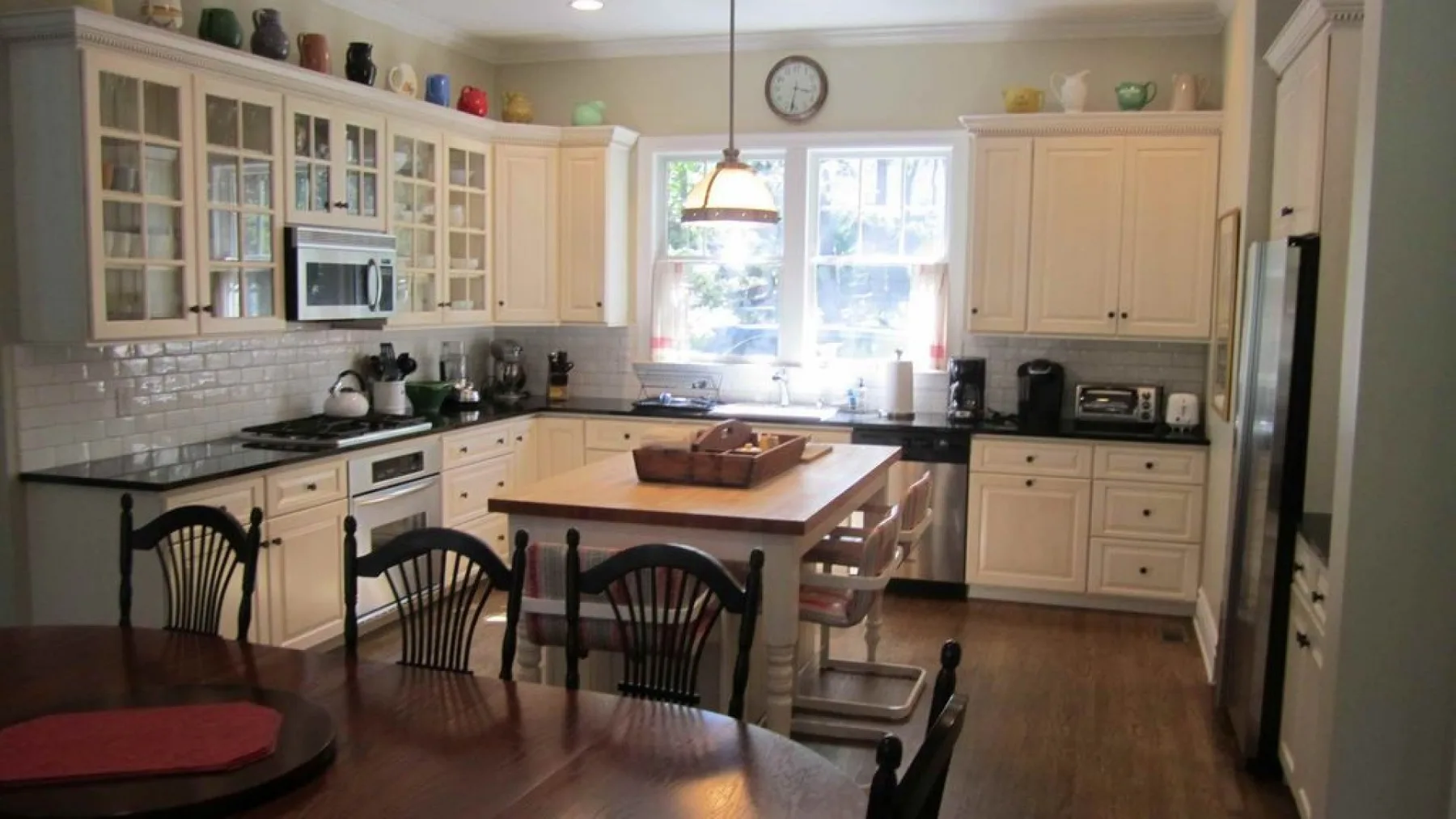 A bright kitchen with white cabinets, a central island, and a dining table.