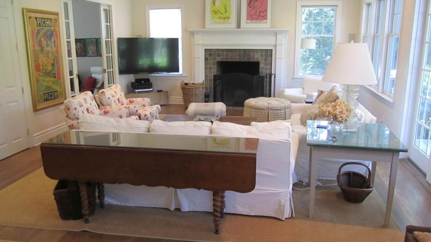 A bright living room with seating arranged around a fireplace and television.