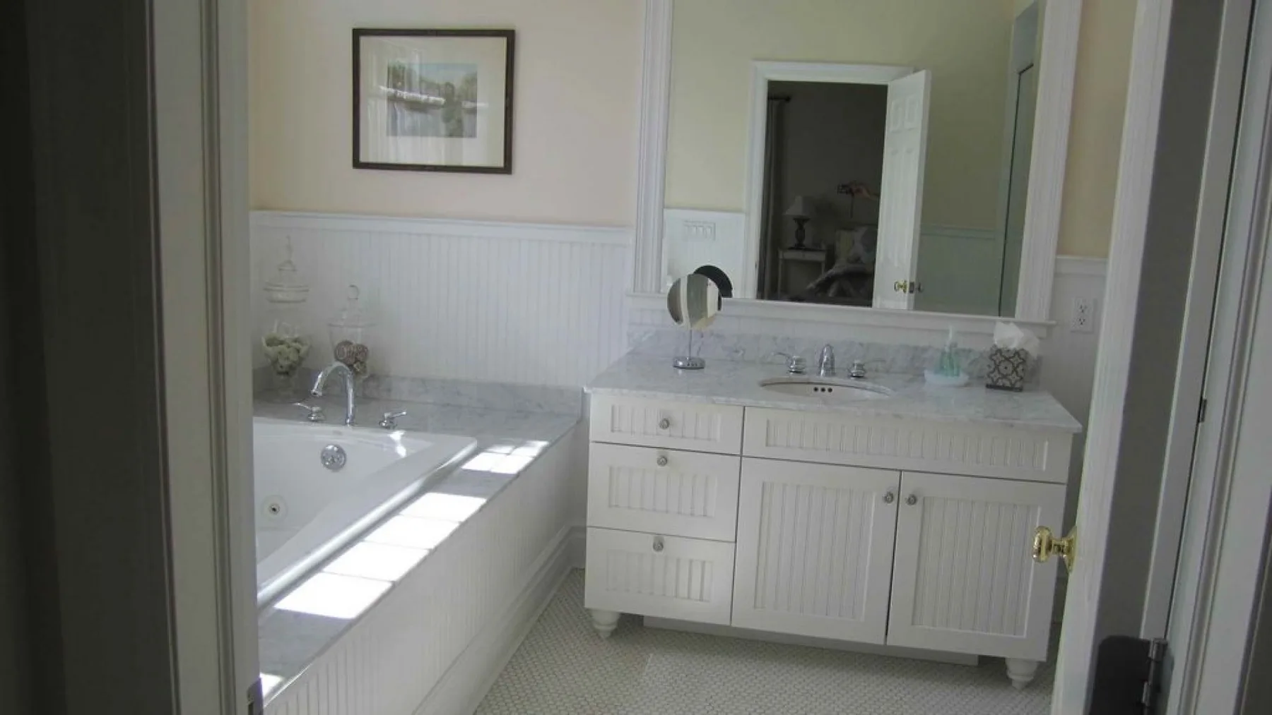 A bathroom with a bathtub and a white vanity beneath a mirror.