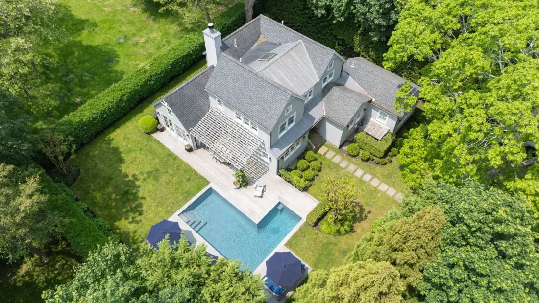 Vista aérea de una casa con piscina, rodeada de árboles y césped.