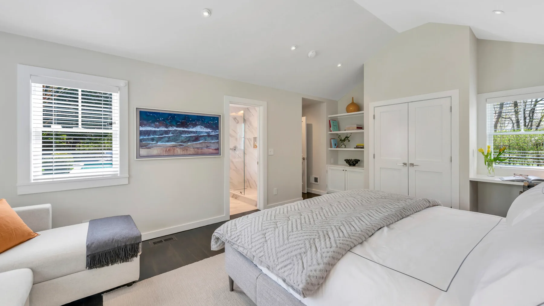 Un dormitorio con una cama grande, una ventana y una pequeña zona de estar.