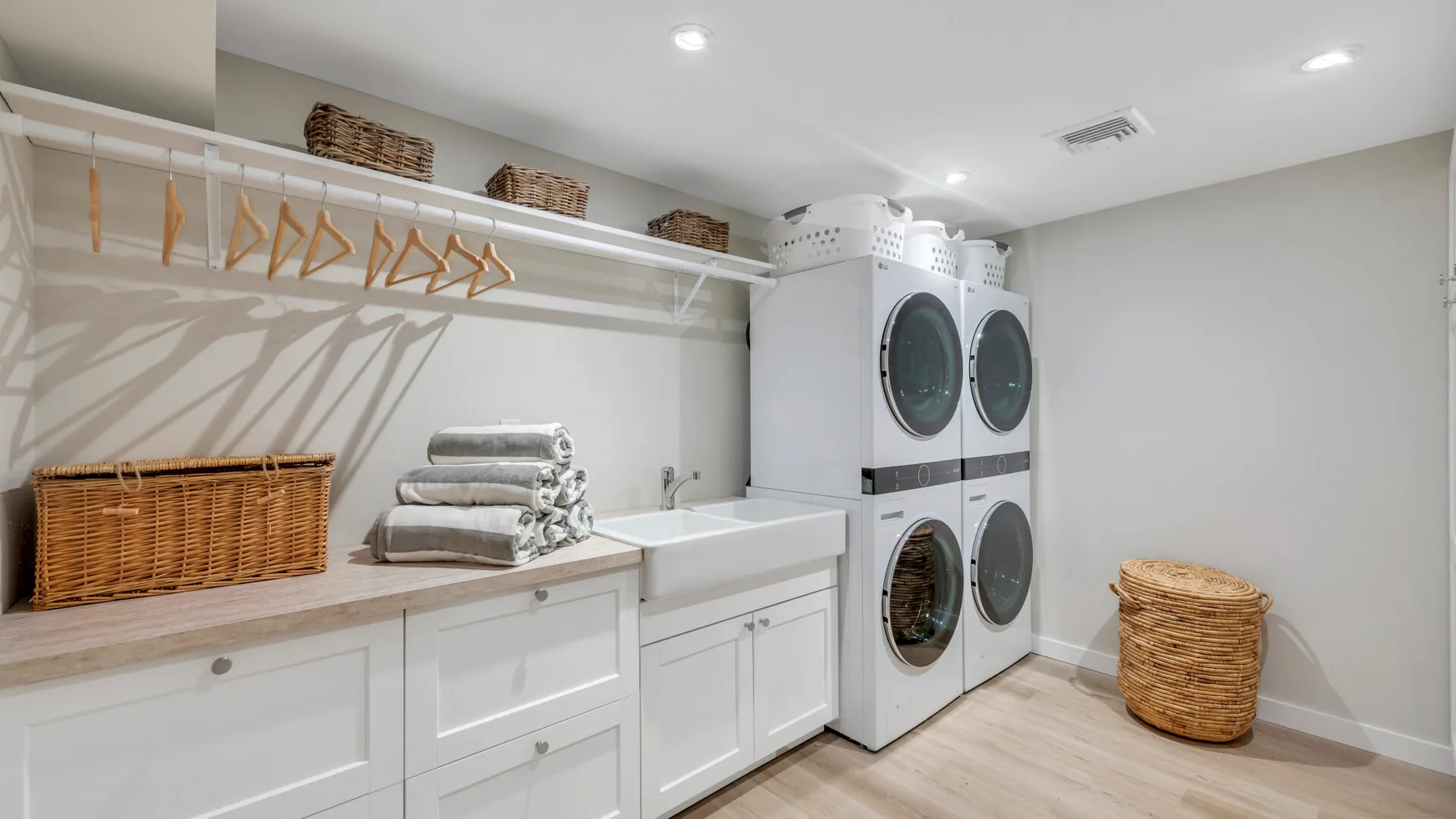 Un cuarto de lavandería con lavadoras apiladas, una encimera para doblar ropa y espacio para colgar prendas.