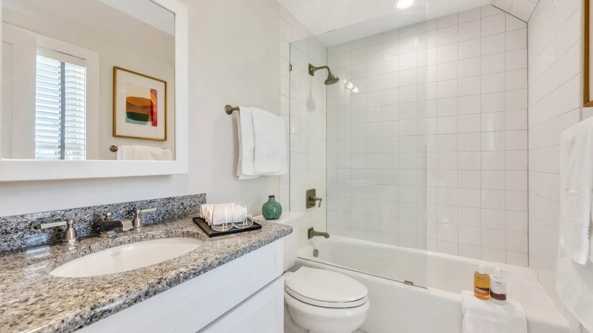 Un baño luminoso con azulejos, lavabo, inodoro y bañera.