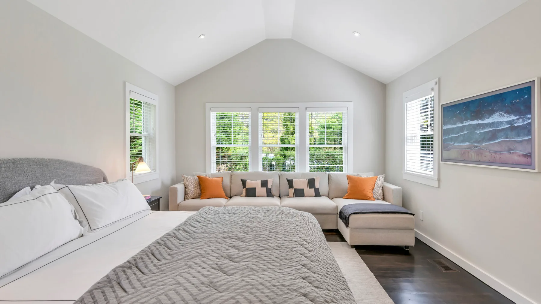 Un dormitorio luminoso con una cama grande, una zona de estar y ventanas.