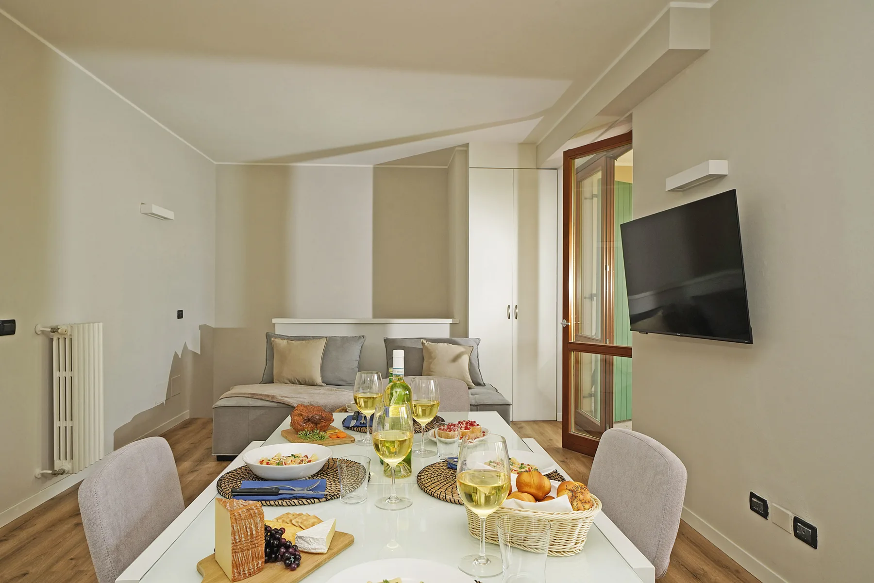 A dining area with a table set with food and seating beside a wall-mounted television.