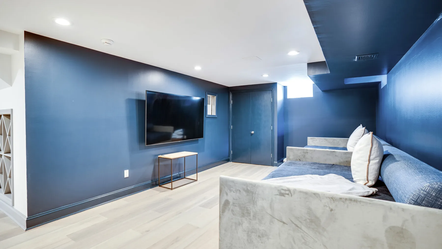 A blue living room with a wall-mounted television and seating.