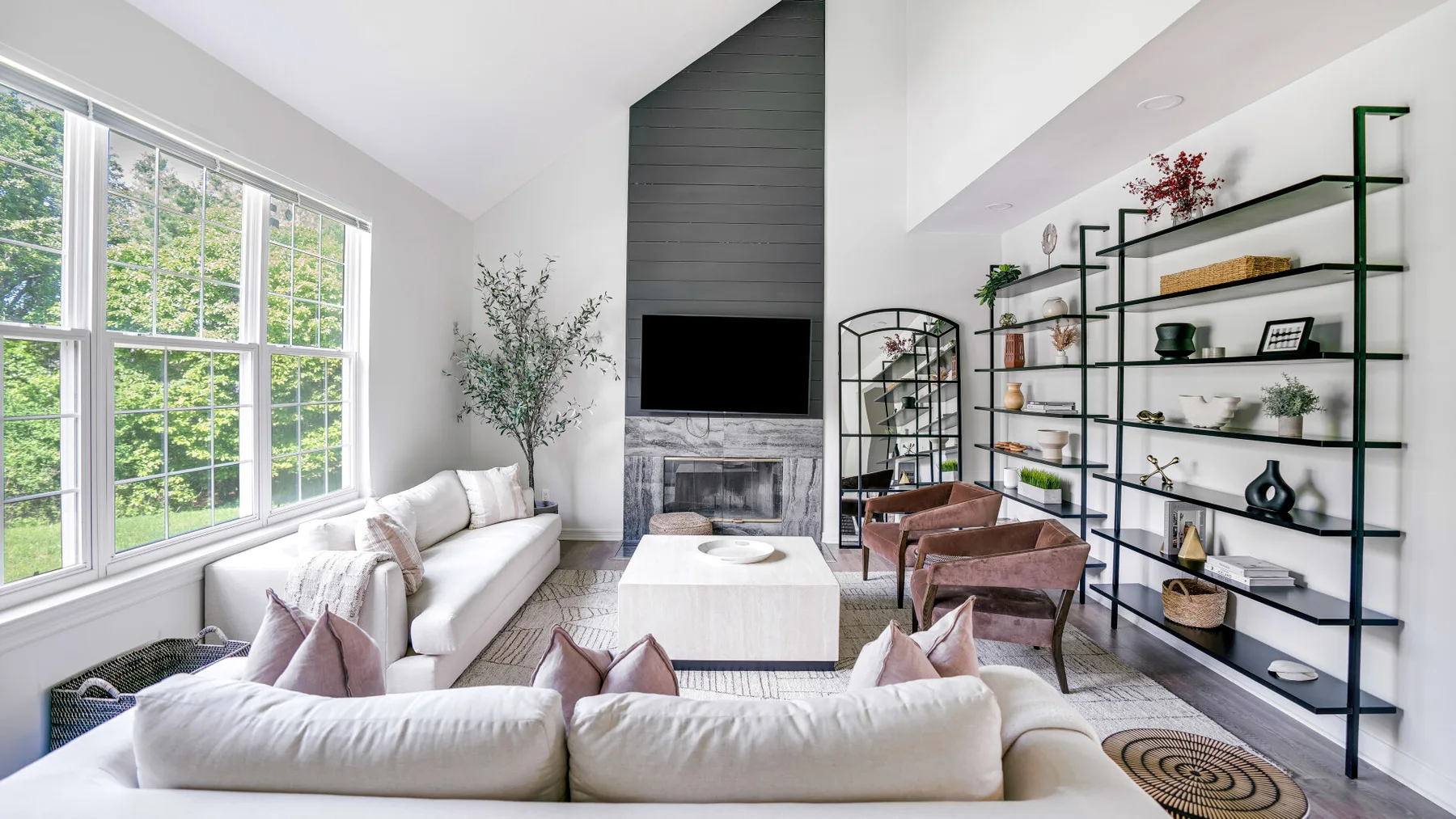 A bright living room with large windows, seating, and a fireplace.