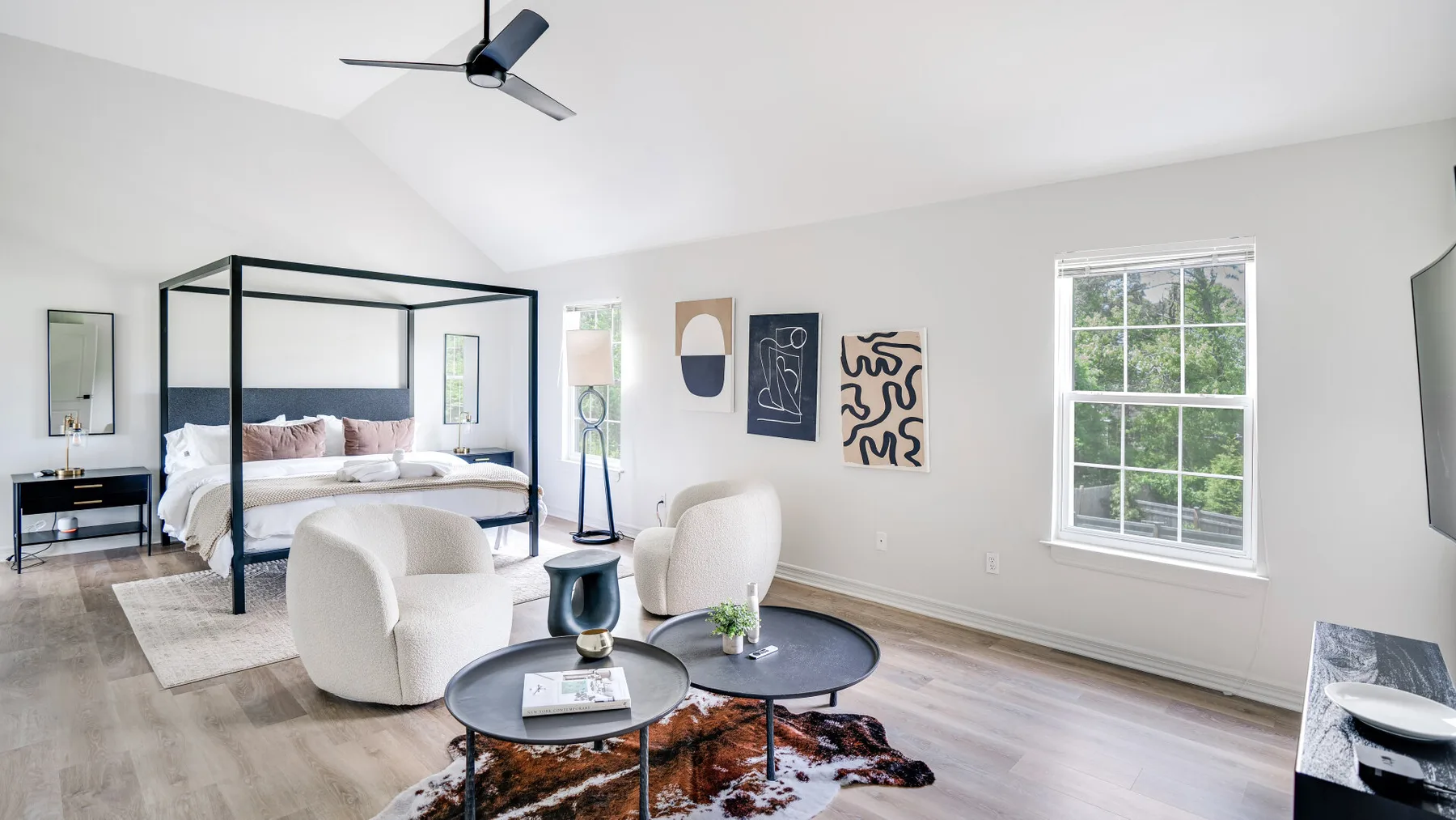 A bright bedroom with a canopy bed and a small seating area by the window.