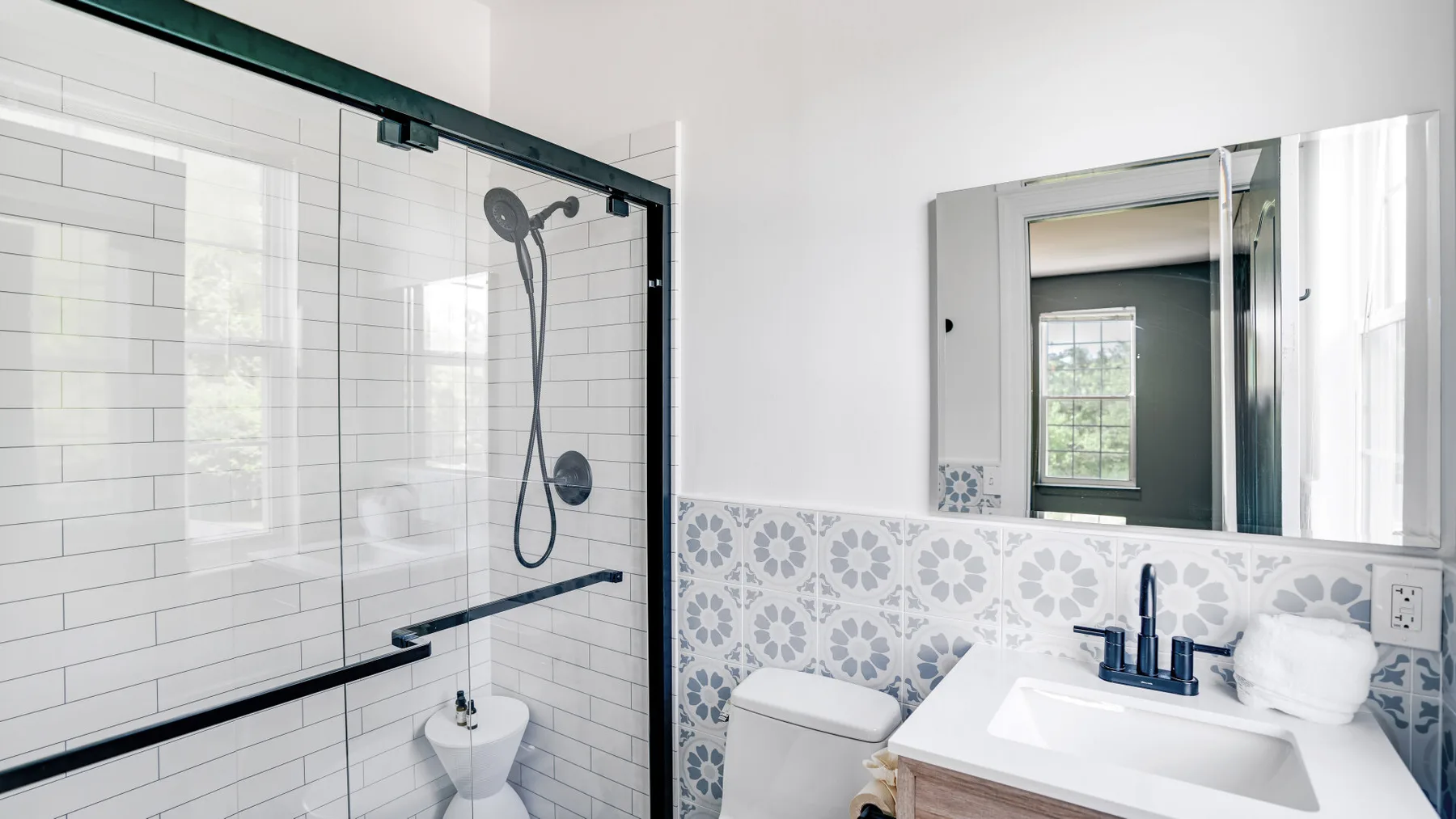 A bright bathroom with a glass shower, toilet, and sink.