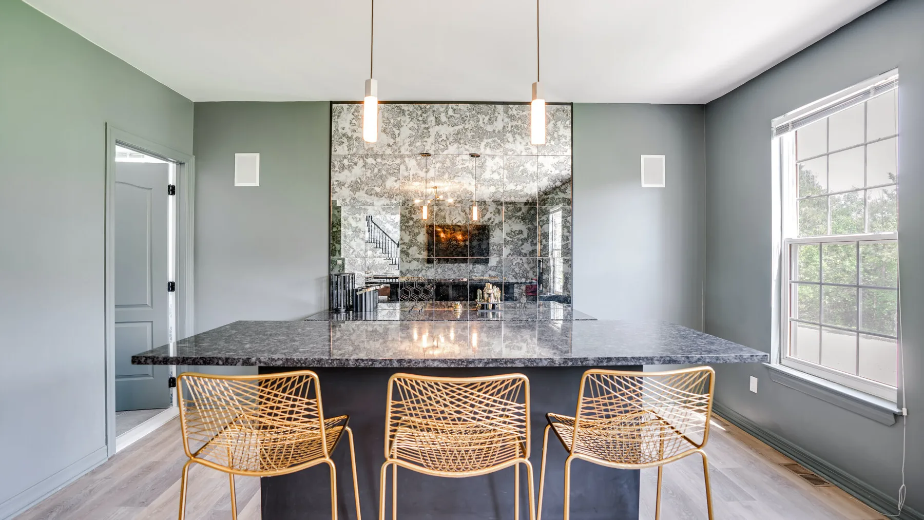 A dining area with a dark table, woven seating, and pendant lights.