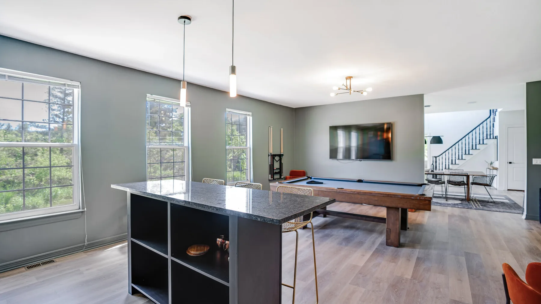 A bright open-plan game room with a pool table and a large island.