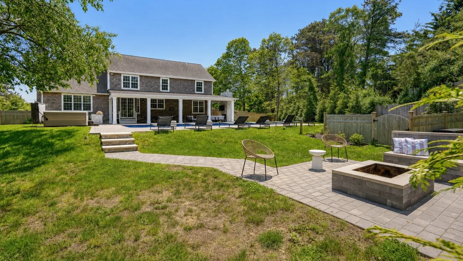 A house and backyard patio with outdoor seating and a fire pit.