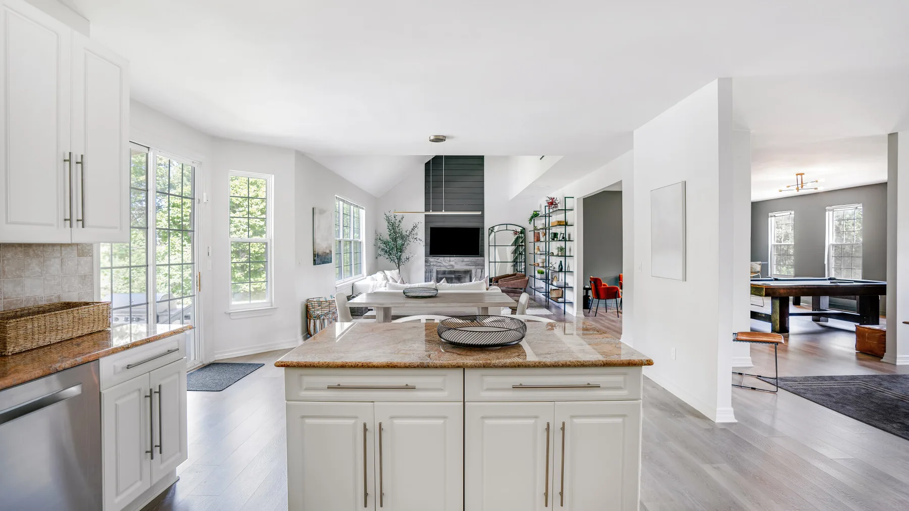 A bright open-plan kitchen with a central island and dining area beyond.