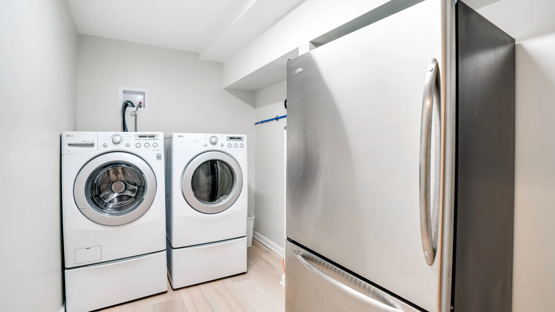 A laundry room with a front-loading washer and dryer beside a large appliance.