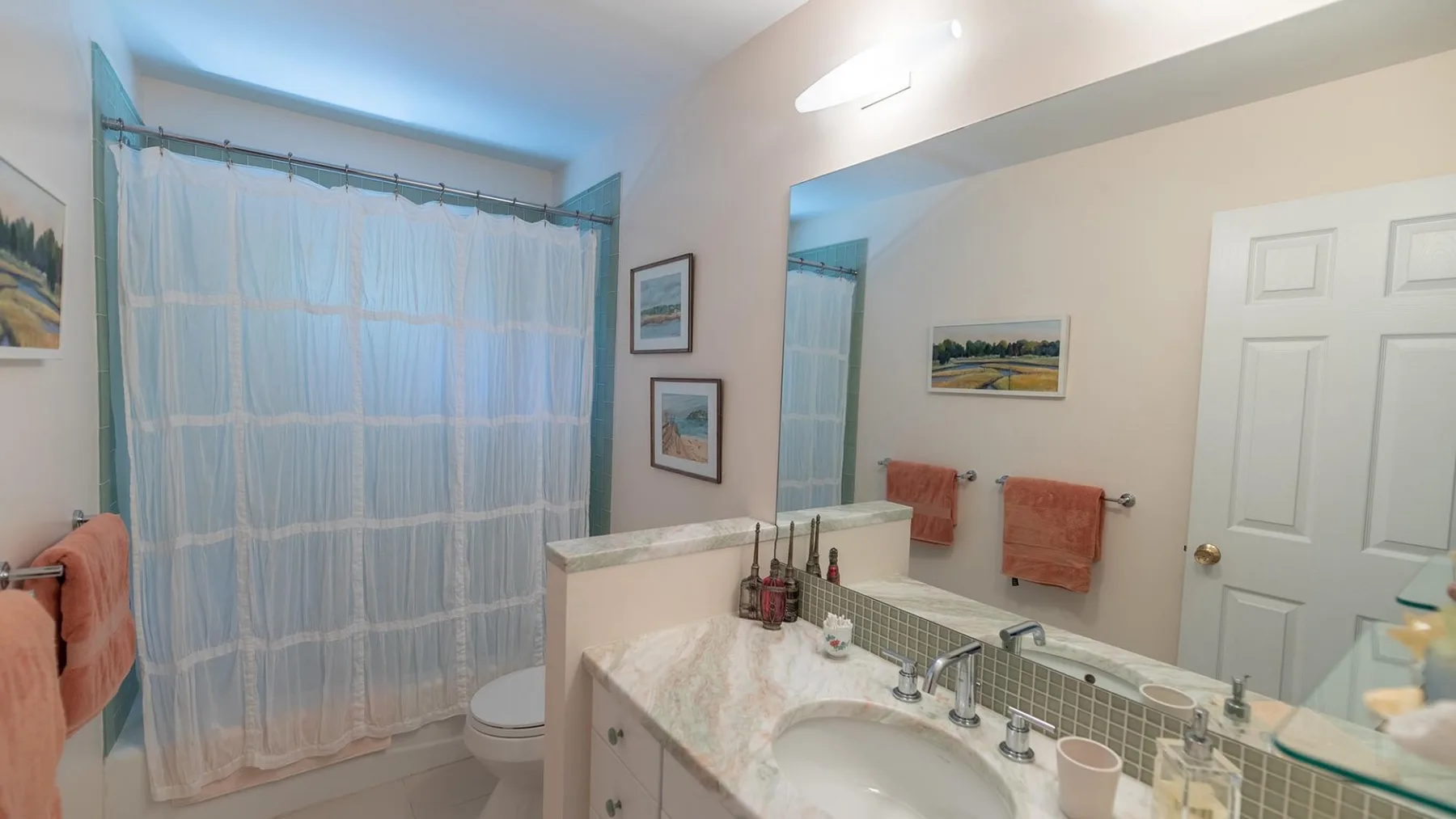 A bathroom vanity and sink sit beside a curtained bathtub and toilet.